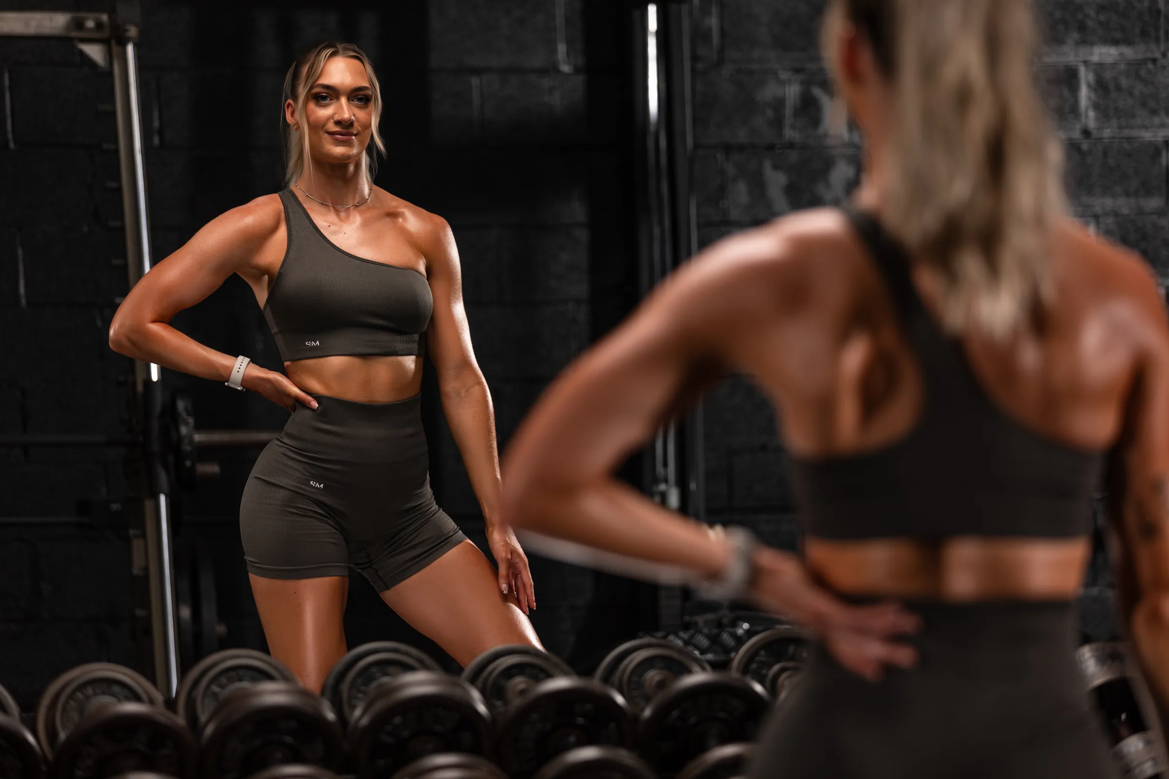 Lara coaching a client beside the dumbbell rack at TNT Elite in Lancaster